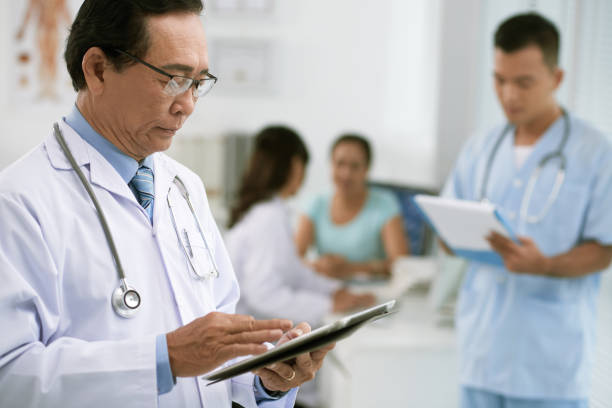 aged vietnamese general practitioner using tablet computer