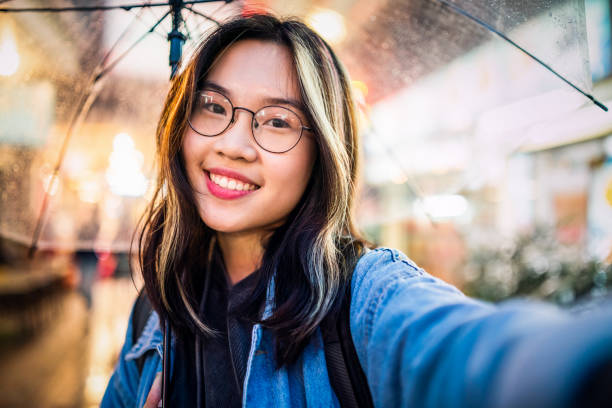 asian girl taking a selfie in rain.